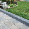 Grey concrete curbs separating grass and concrete paving stones