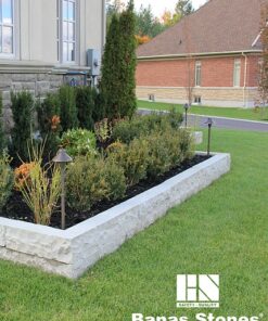 garden bed lined with grey natural stone curbs in front of lawn