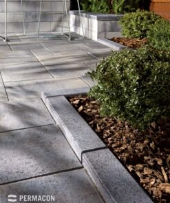 grey concrete curbs separating mulched garden bed and paving stone patio