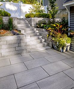 Tiered retaining wall and stair case made out of concrete wall blocks made to look like natural stone